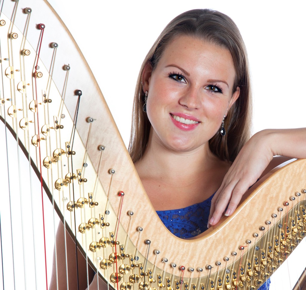 young caucasian woman with concert harp in studio against white